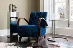 a blue chair sitting on top of a hard wood floor next to a table with a mirror