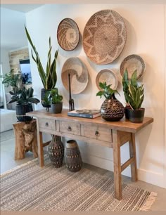 a wooden table topped with potted plants next to a wall covered in wicker baskets