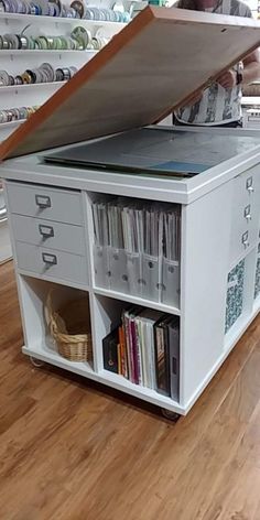 a man standing next to a book shelf with a large open drawer on top of it