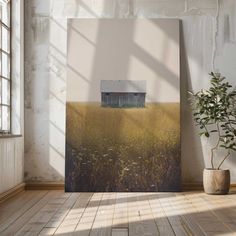 an empty room with a painting on the wall and a potted plant next to it