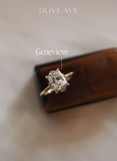 an engagement ring sitting on top of a wooden box with the words genevieve written below it