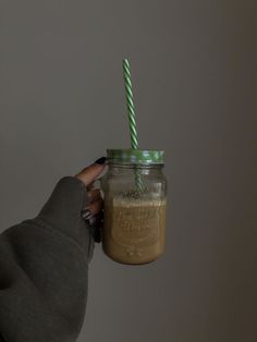 a person holding a mason jar with a green and white straw