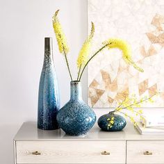 three vases with yellow flowers are sitting on a white dresser in front of a painting