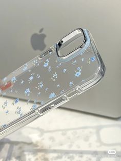 a clear case with blue flowers on it is sitting next to an apple macbook