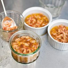 three small containers filled with food sitting on top of a metal counter next to two spoons