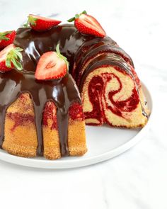 a bundt cake with chocolate icing and sliced strawberries on the top is sitting on a plate