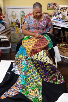 a woman sitting in a room working on a piece of cloth