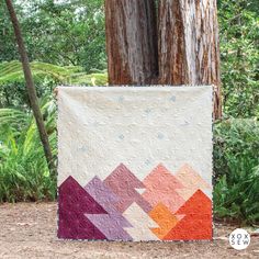 a colorful quilt hanging from a tree in the woods with text overlay that reads free pattern