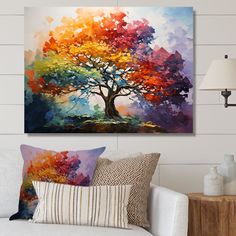 a colorful tree painting hanging on the wall above a white couch with pillows and lamps