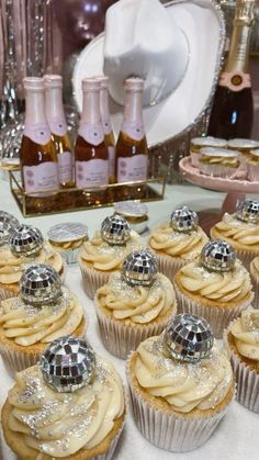 some cupcakes are sitting on a table with bottles of champagne in the background