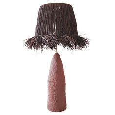 a lamp that is made out of straw and has a brown shade on the top