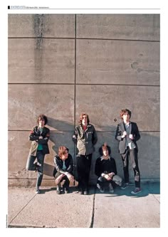 four people are posing for a photo in front of a concrete wall with their arms around each other