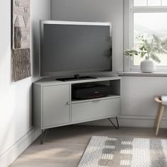 a flat screen tv sitting on top of a wooden cabinet in front of a window