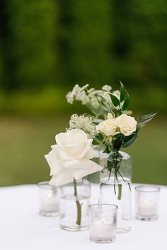 white flowers and greenery in vases on a table