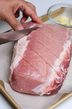 a person cutting meat with a knife on a tray