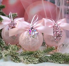 three pink christmas ornaments with bows on them