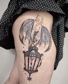 a woman's thigh with a bat and lantern tattoo on the side of her leg