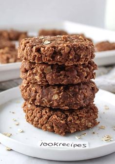 three cookies stacked on top of each other in front of a white plate with oatmeal