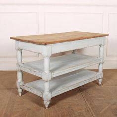 an old wooden table with two shelves on it's sides, against a white wall