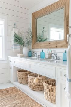 a bathroom with two baskets under the sink and a large mirror over the vanity in front of it