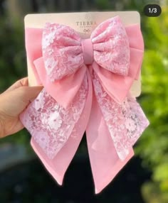 a hand holding up a pink bow with lace on the front and back of it