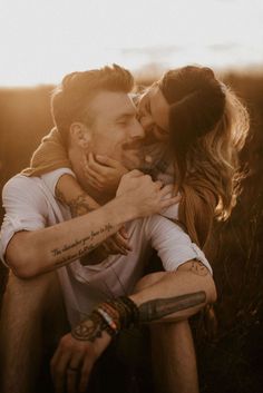 a man holding a woman in his arms while she is kissing her forehead with the sun behind him