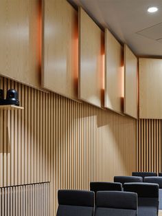 an empty lecture hall with blue chairs and wooden paneling on the wall behind it