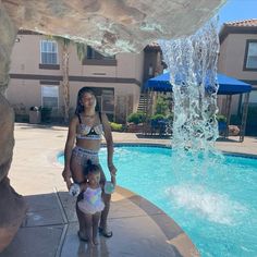 a woman and child standing in front of a pool