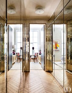 the inside of an office building with mirrored walls and wooden floors, two chairs are in the middle