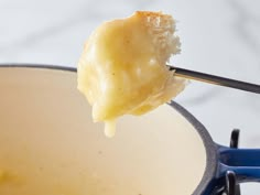 a spoonful of cheese being lifted from a saucepan