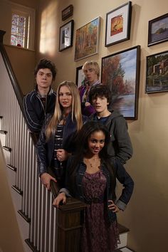 a group of young people standing on the stairs in front of pictures hanging on the wall