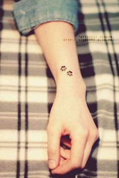 a person with a small paw tattoo on their wrist