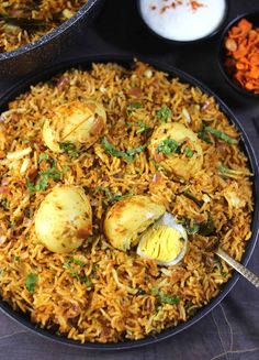 a plate full of rice and eggs with other dishes in the background on a table