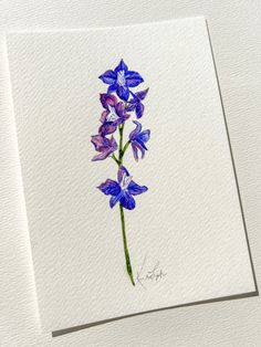 a blue and purple flower is shown on a white paper with watercolor pencils