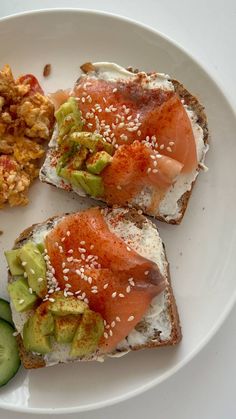 two pieces of bread with salmon and cucumber on it, along with other food items