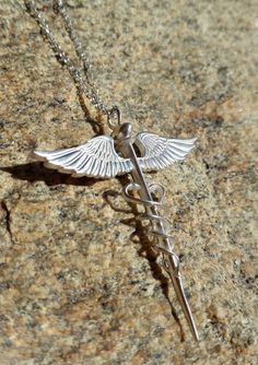 a silver cadus necklace on a rock