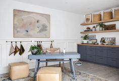 a living room with a blue table and two stools in front of the wall