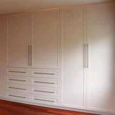 an empty room with white cabinets and wood floors