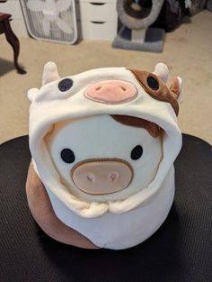 a stuffed cow with a hood on it's head is sitting on a table