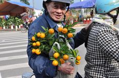 an old man is handing oranges to a woman on a scooter in the street