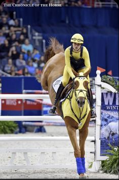 a man riding on the back of a brown horse next to a white and blue sign