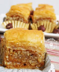 some tasty looking pastries sitting on top of a paper plate with muffins in the background