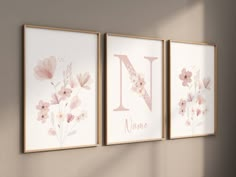 three framed art prints with flowers and the letter n in pink on a beige wall