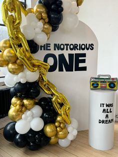 the balloon arch is decorated with black, white and gold balloons