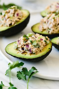 two avocados with tuna salad on them are sitting on a plate next to a fork