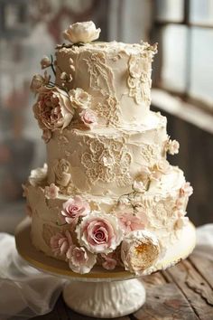 a three tiered wedding cake with pink flowers on the top and bottom, sitting on a wooden table