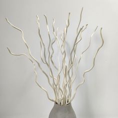 a gray vase with white branches in it on a table next to a black and white wall