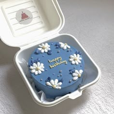 a blue birthday cake in a plastic container