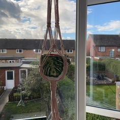 a hanging planter in front of a window with a view of the back yard