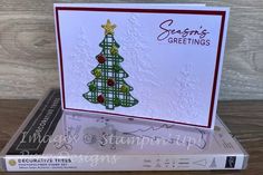 a card with a christmas tree on it sitting on top of a stack of books